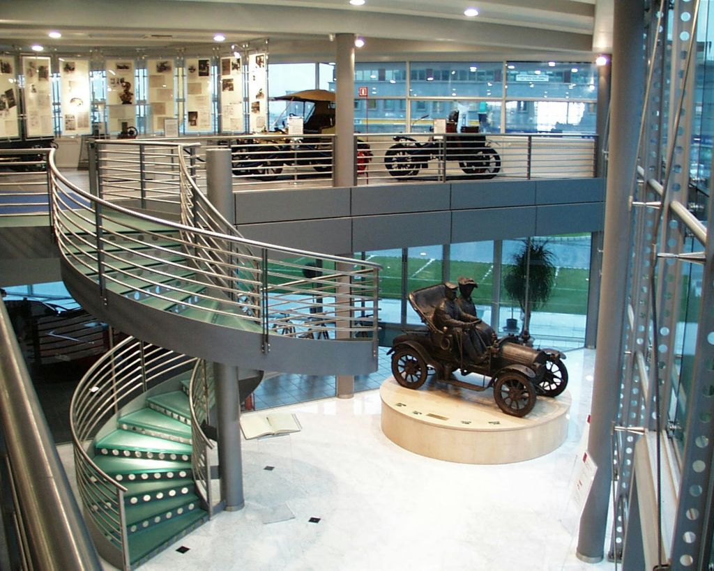 나선형 계단, 유리벽, 빈티지 자동차 전시, 클래식 차량 전시가 있는 실내 박물관이 두 층으로 나뉘어 있습니다.