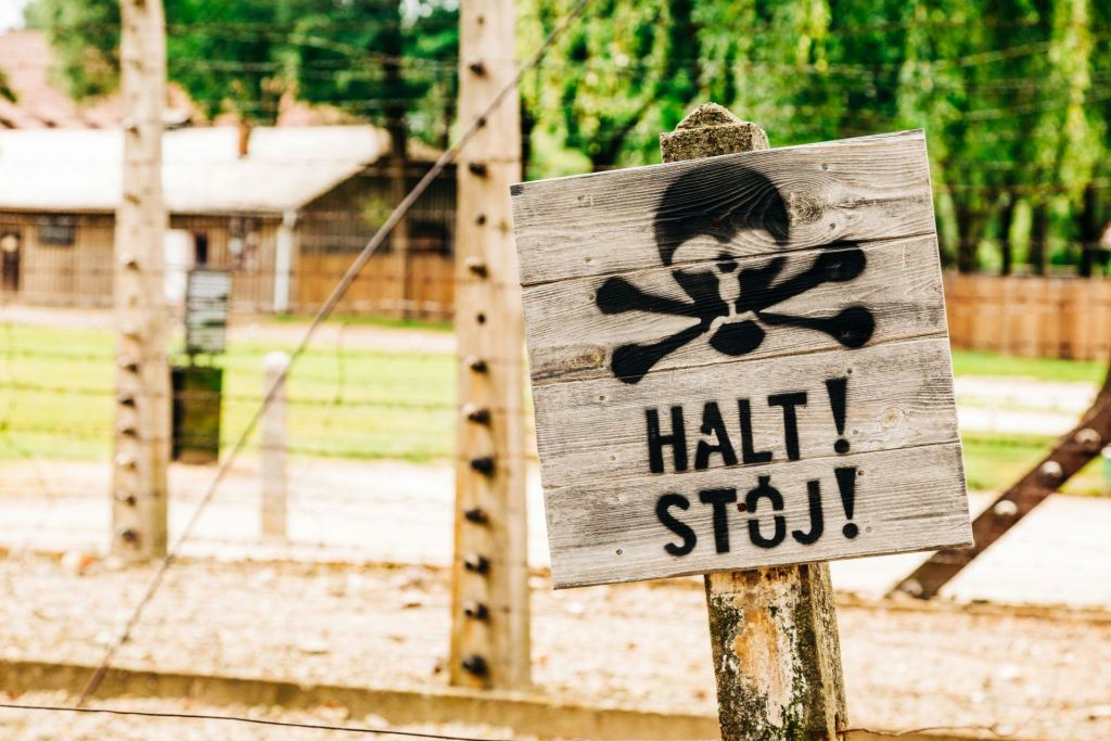 두개골과 십자뼈가 있는 나무 표지판과 'HALT! 울타리 앞에 있는 Stój! '