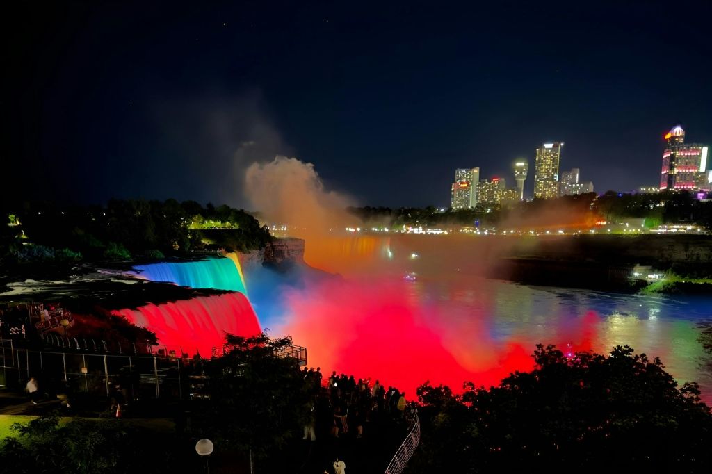 나이아가라 폭포의 야경은 화려한 조명과 도시 건물, 수많은 사람들로 가득합니다.