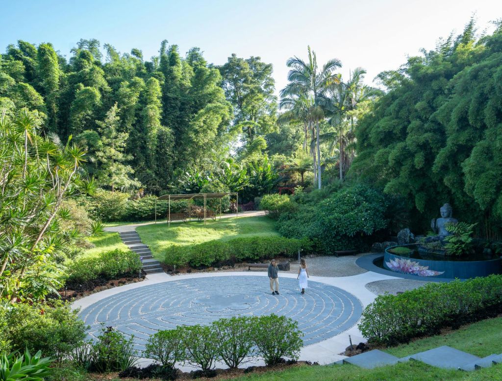 울창한 녹음과 나무가 우거진 풍경의 정원에서 나선형 길을 걷고 있는 두 사람.