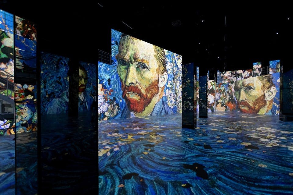 빈센트 반 고흐의 자화상과 소용돌이치는 패턴을 여러 개의 미러 패널에 투영한 디지털 아트 전시.