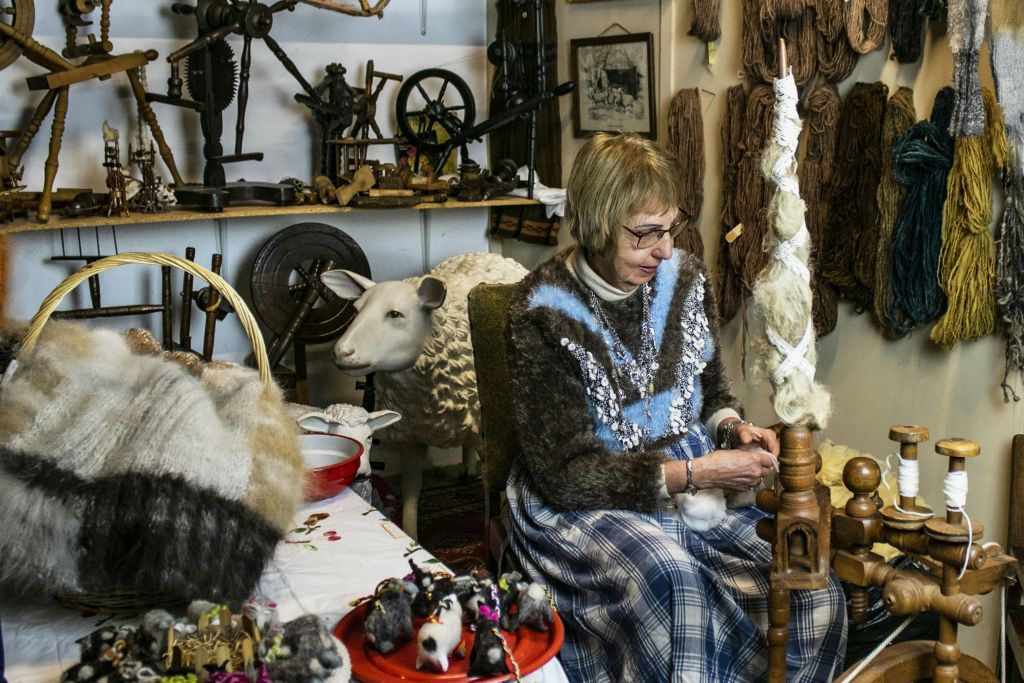 털실, 흰 양 동상, 양모 관련 물품이 놓인 어수선한 방에서 한 노파가 양모를 돌리고 있다.