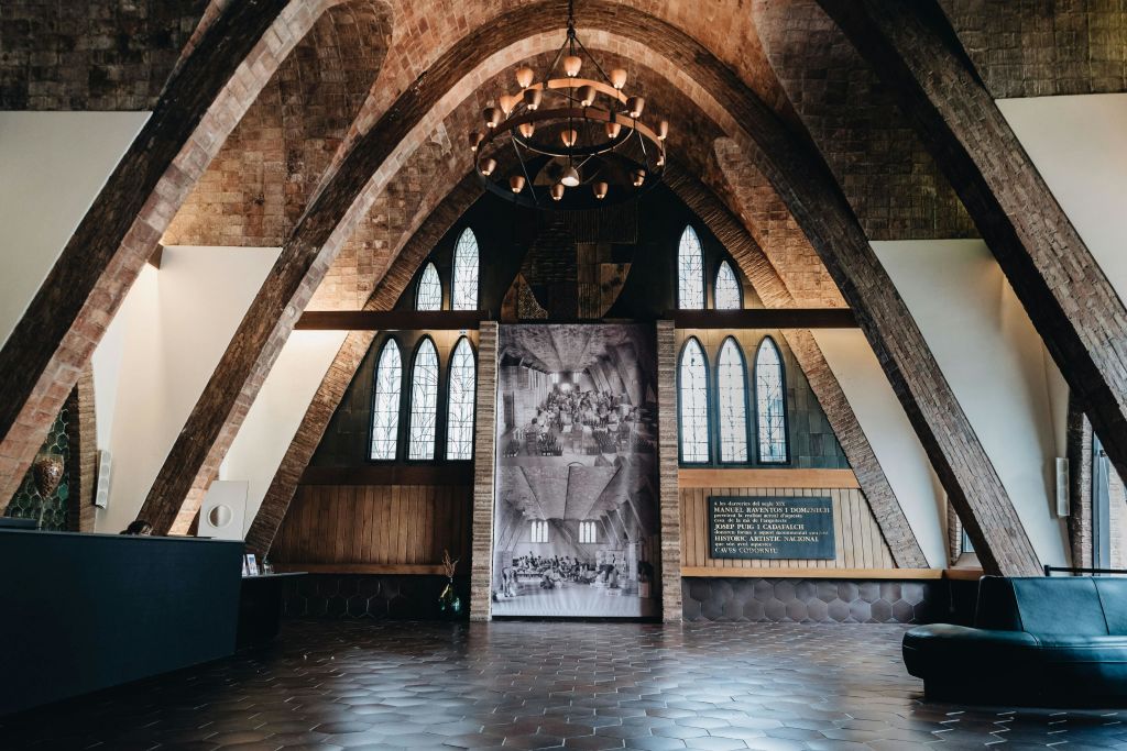 아치형 천장, 샹들리에, 스테인드글라스 창문, 대형 사진 디스플레이, 나무 패널 벽이 있는 객실입니다.