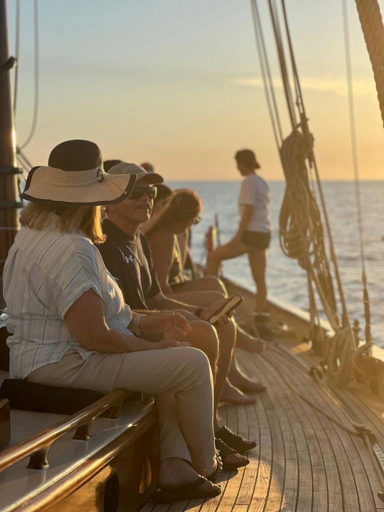 해 질 녘 보트 갑판에 앉아 서 있는 사람들. 밧줄과 바다를 배경으로 말이죠.