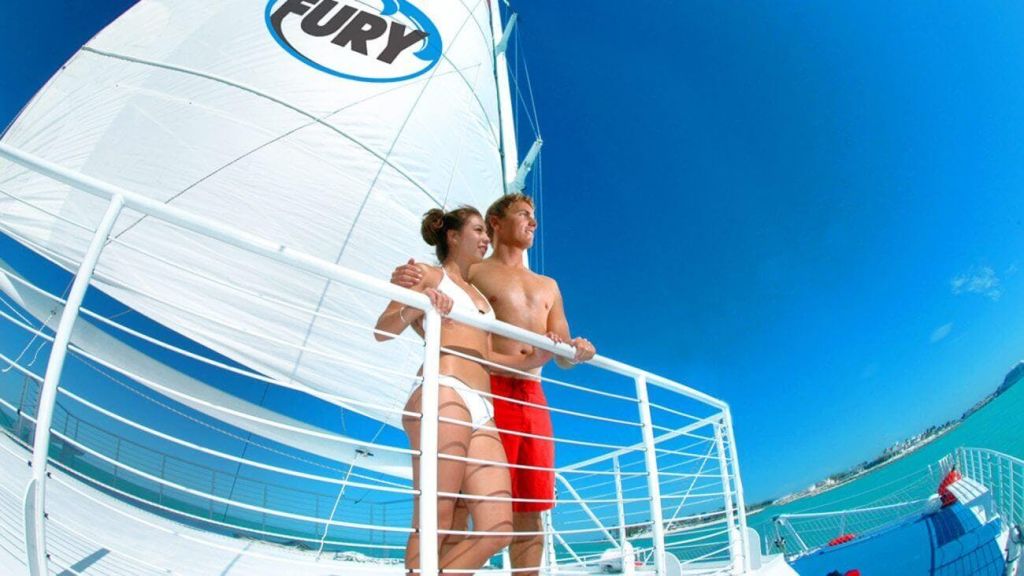 흰색 수영복을 입은 여성과 빨간색 반바지를 입은 남성이 맑고 푸른 하늘을 배경으로 '분노' 라는 돛을 단 범선에 서 있습니다.