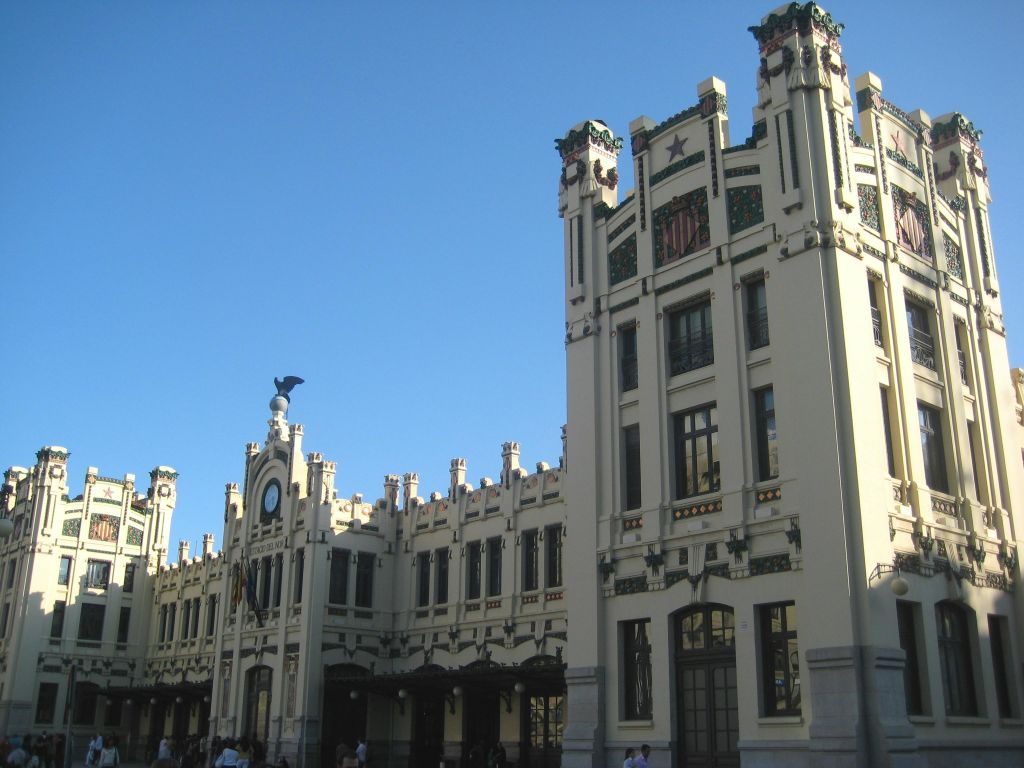 높은 타워와 화려한 장식이 돋보이는 웅장한 아트 데코 건물로, 맑고 푸른 하늘을 배경으로 정면에 시계가 놓여 있습니다.