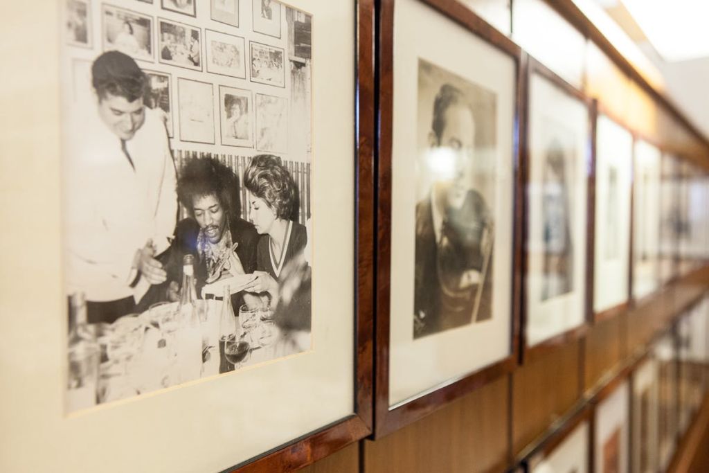 한 남자가 음식을 제공하고 다른 남자가 테이블에 앉아 있는 세 사람의 흑백 사진 액자.