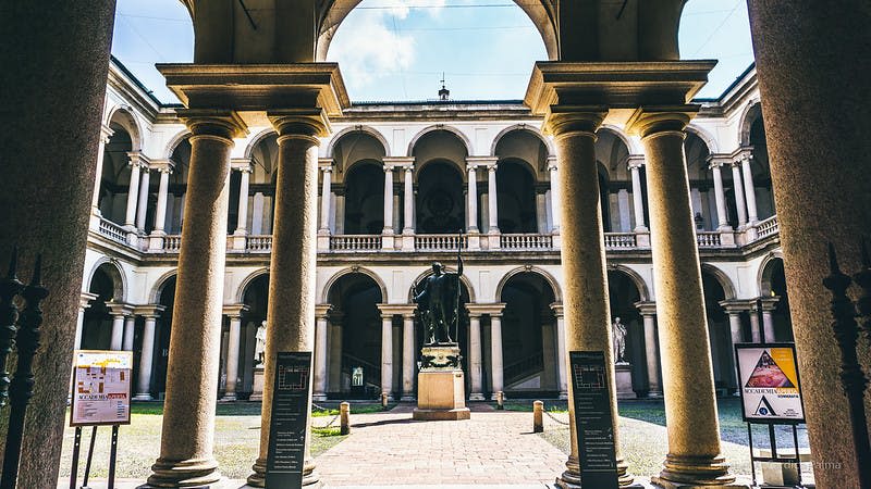 커다란 기둥이 있는 아치형 마당, 중앙 동상, 2층 건물에 아치형 통로가 여러 개 있습니다.