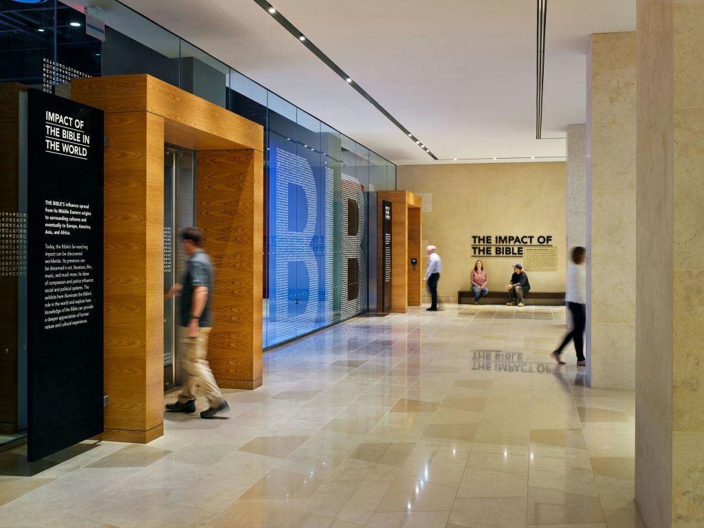 사람들이 걷고 앉을 수 있는 로비 공간. 표지판에는 "성경의 영향" 이라고 쓰여 있습니다. "성경" 텍스트가 있는 대형 유리 디스플레이.