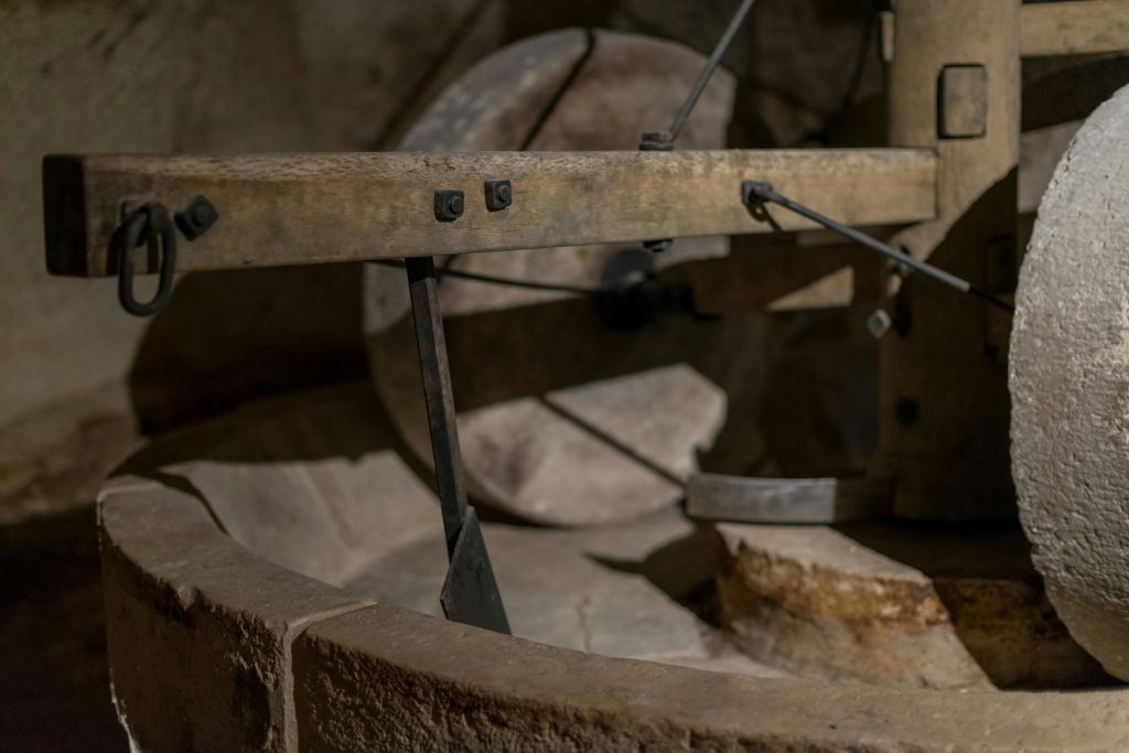 저조도에서 목재 및 금속 부품을 사용한 소박하고 구식의 맷돌 그라인더를 클로즈업하여 풍화된 질감을 보여줍니다.