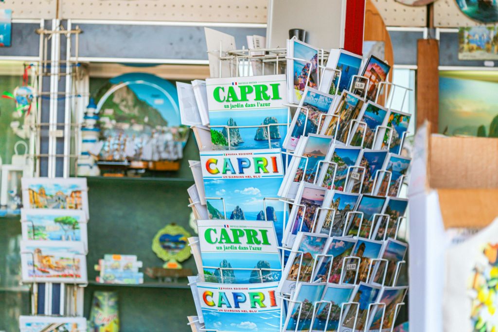 다채로운 색상의 엽서와 여행 안내 책자가 있는 진열대로, 관광 안내소에서 카프리에 대한 이미지와 텍스트가 담겨 있습니다.