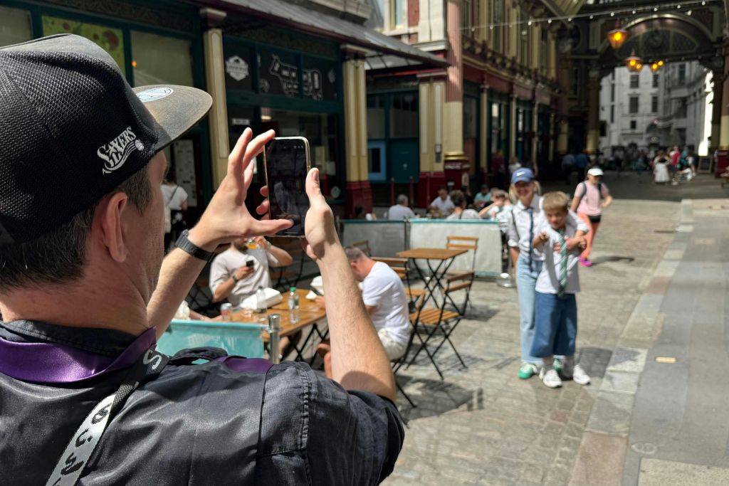 테이블과 의자가 놓인 활기찬 야외 시장에서 사진을 찍는 동안 두 사람이 사진 촬영을 위해 포즈를 취하고 있습니다.