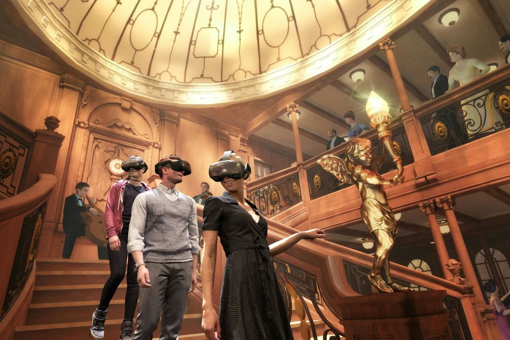 나무 디테일과 돔형 천장이 있는 화려하고 유서 깊은 스타일의 방에서 VR 헤드셋을 착용한 한 무리의 사람들.