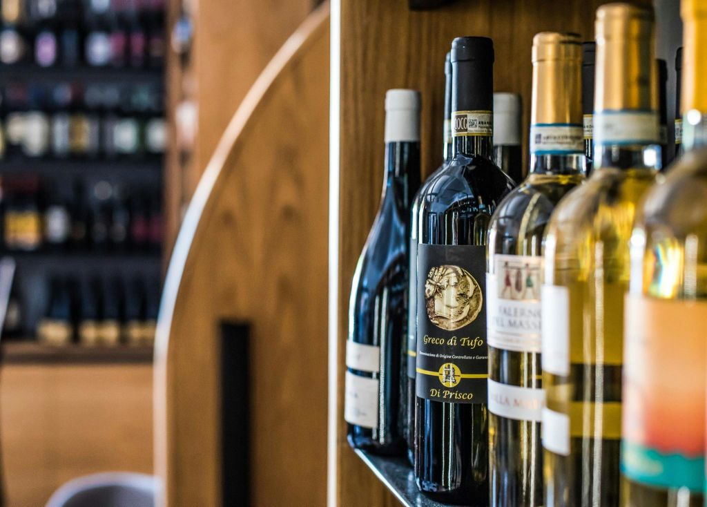 나무 배경이 있는 와인 가게의 선반에 와인이 진열되어 있습니다.