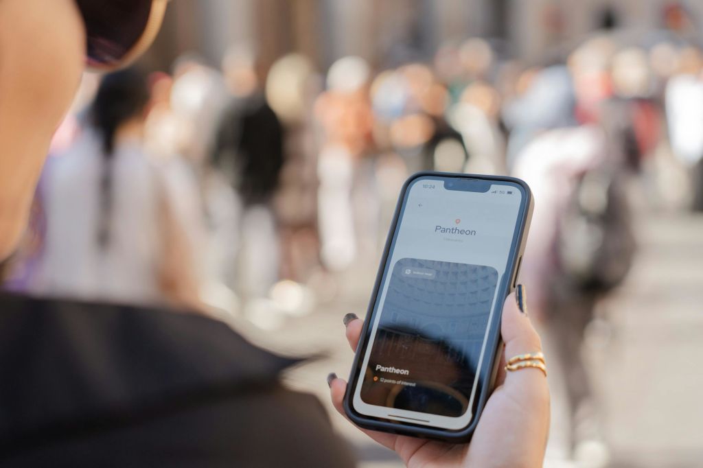 야외 환경에서 흐릿한 군중 앞에서 판테온 앱을 표시하는 스마트폰을 클로즈업합니다.