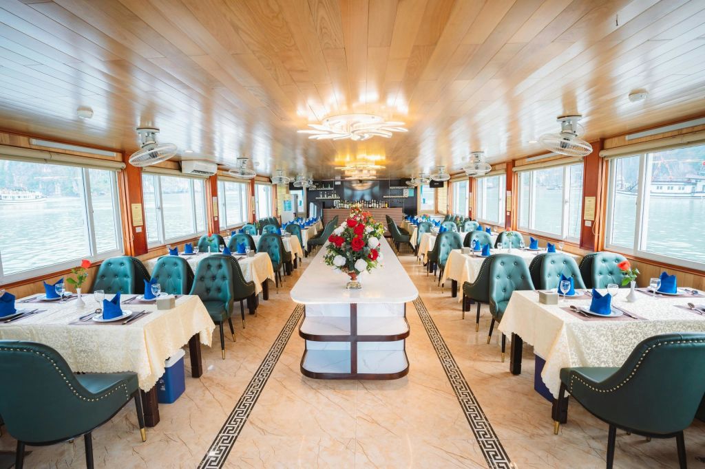 우아한 테이블과 의자, 꽃무늬 센터피스, 자연광이 들어오는 커다란 창문이 있는 넓고 조명이 밝은 식사 공간입니다.