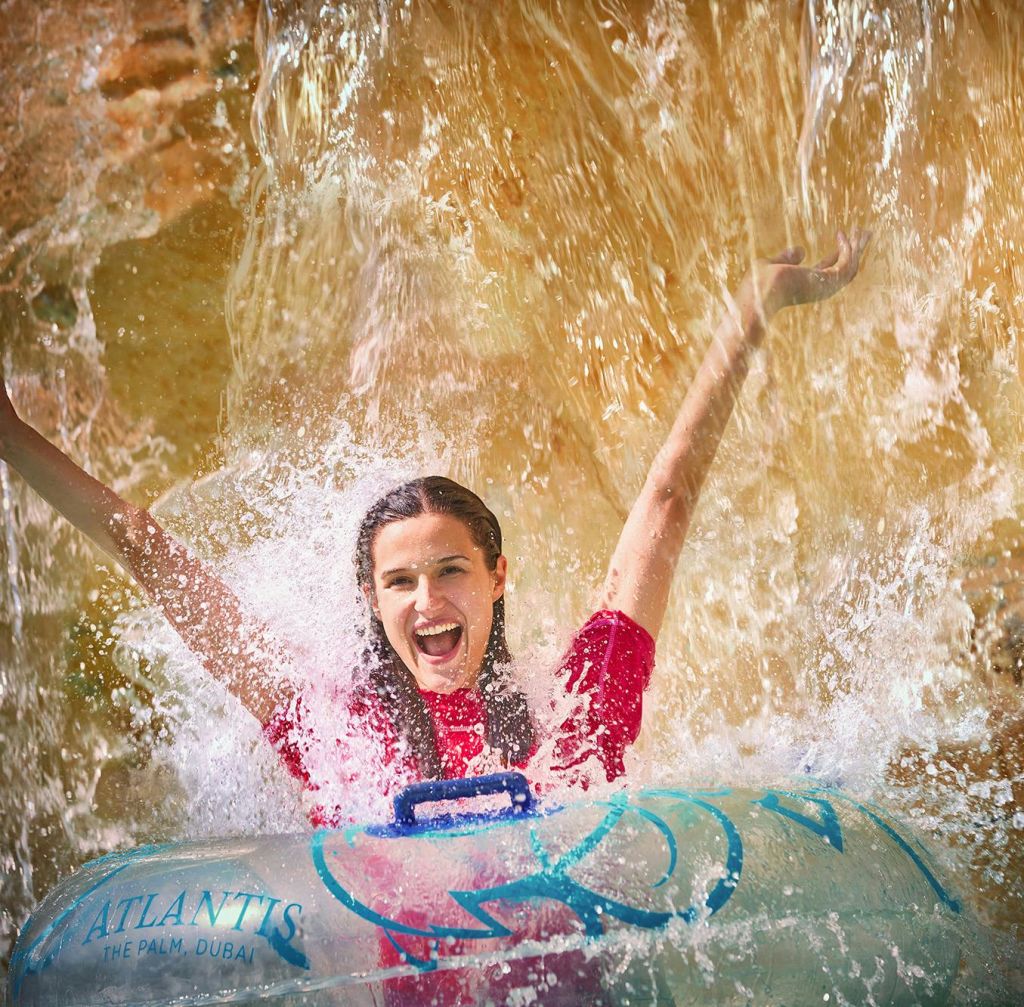두바이의 아틀란티스 더 팜 (Atlantis The Palm) 에서 물놀이를 하며 팔을 기쁘게 들어 올리는 사람.