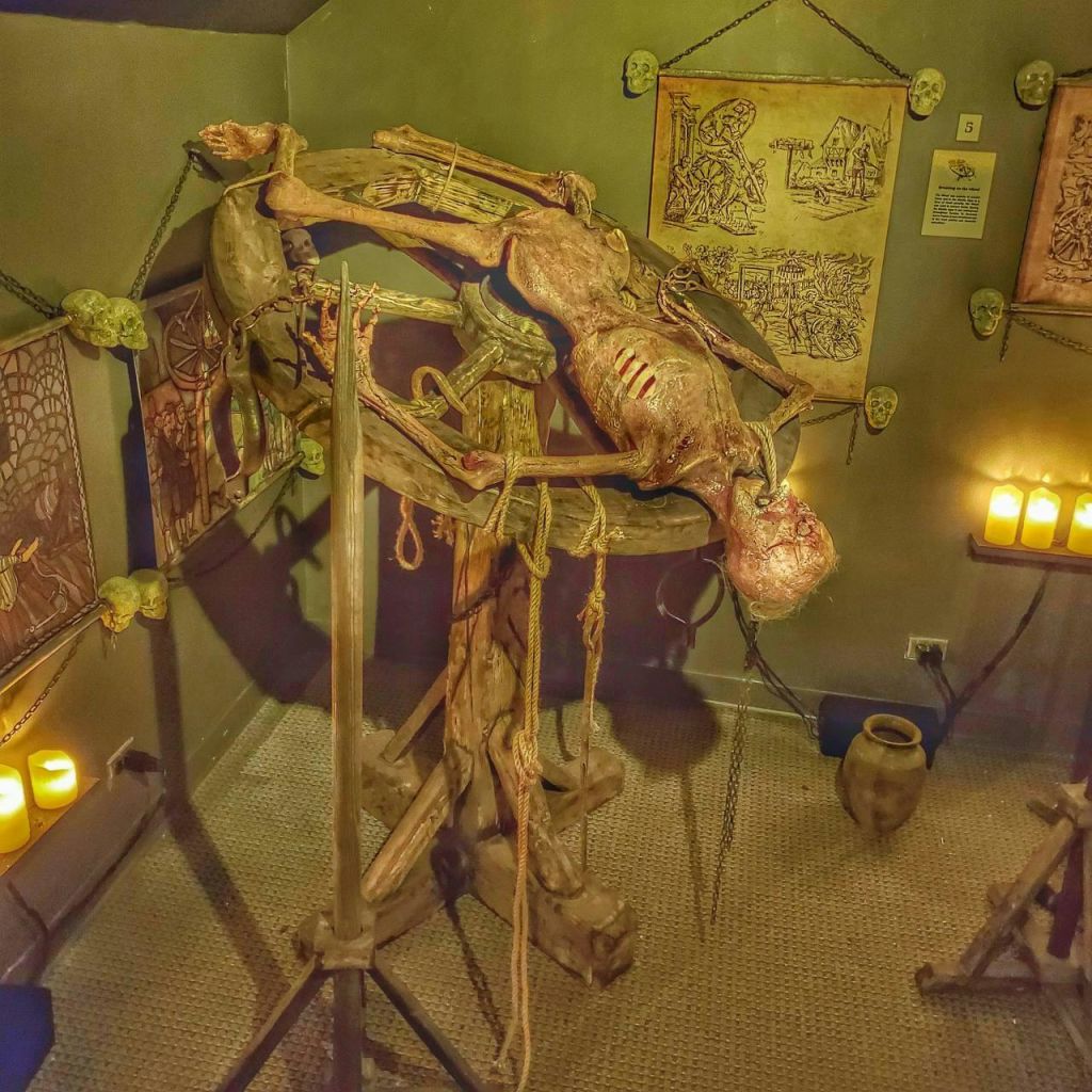 벽에 양초와 고대 스타일의 예술품이 놓인 조명이 희미하고 장식된 방의 나무 프레임에 미라가 그려진 그림입니다.