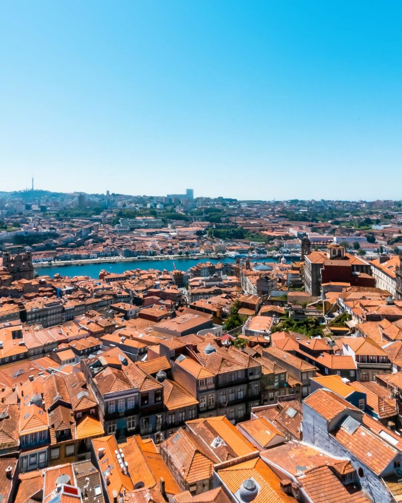 수많은 테라코타 지붕 건물, 중앙을 흐르는 강, 맑고 푸른 하늘이 있는 도시의 공중 전망.