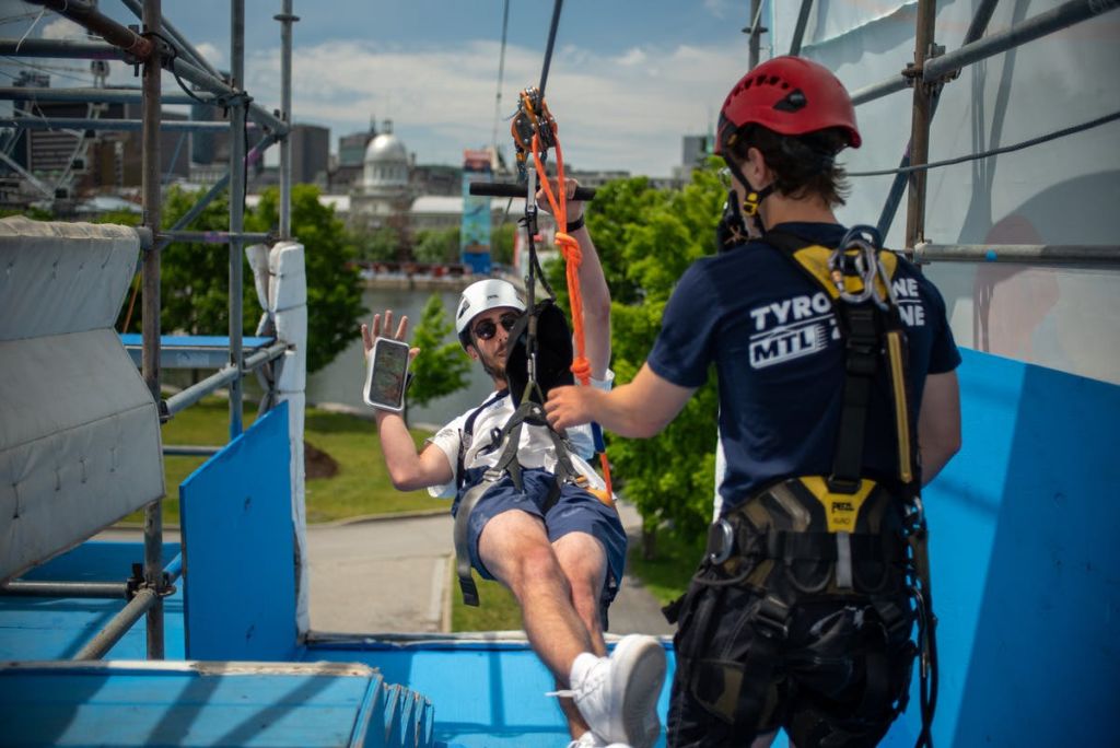 도시 경관과 녹지를 배경으로 강사가 짚라인 타기를 즐기고 있습니다.
