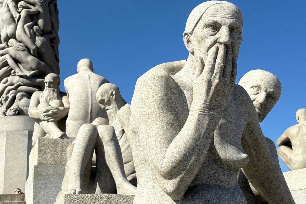 여러 개의 인간 형상의 석조 조각이 서로 밀착되어 있으며, 하나의 형상이 입을 가리고 있습니다. 하늘이 맑고 푸르다.