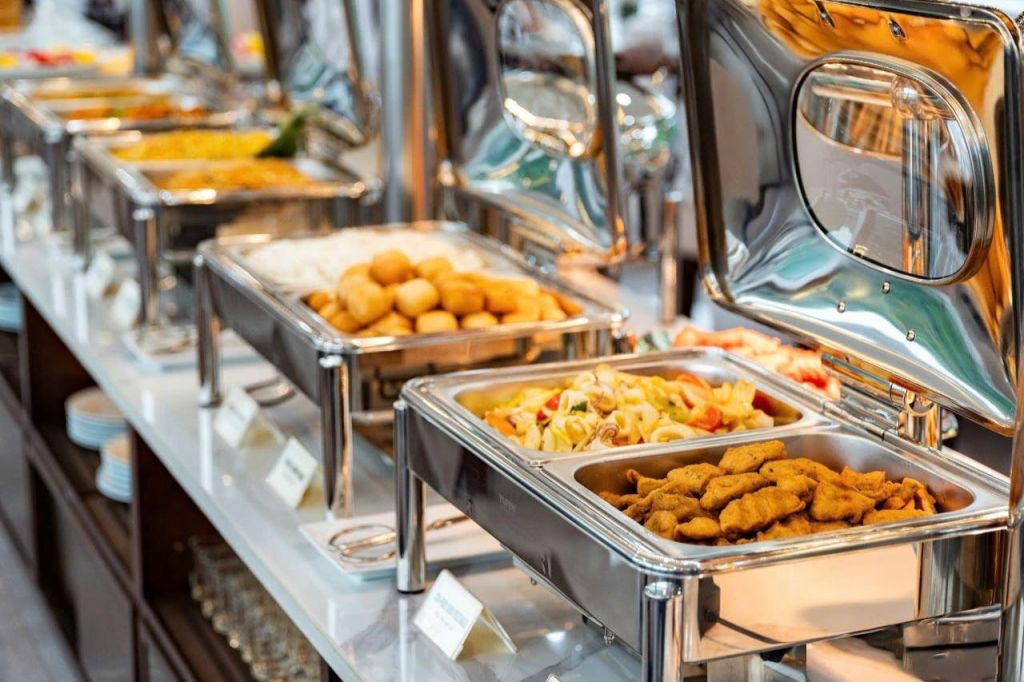 파스타, 튀김, 기타 음식 등 스테인레스 스틸 차핑 요리의 다양한 요리가 담긴 뷔페 테이블입니다.