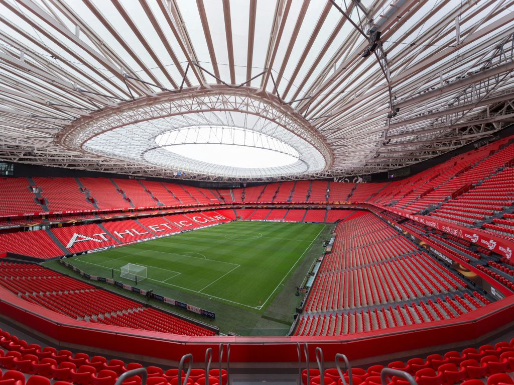 빨간색 좌석, 커다란 지붕, 스탠드에 "ATHLETIC CLUB" 이라고 쓰여진 빈 축구 경기장. 중앙의 녹색 피치.