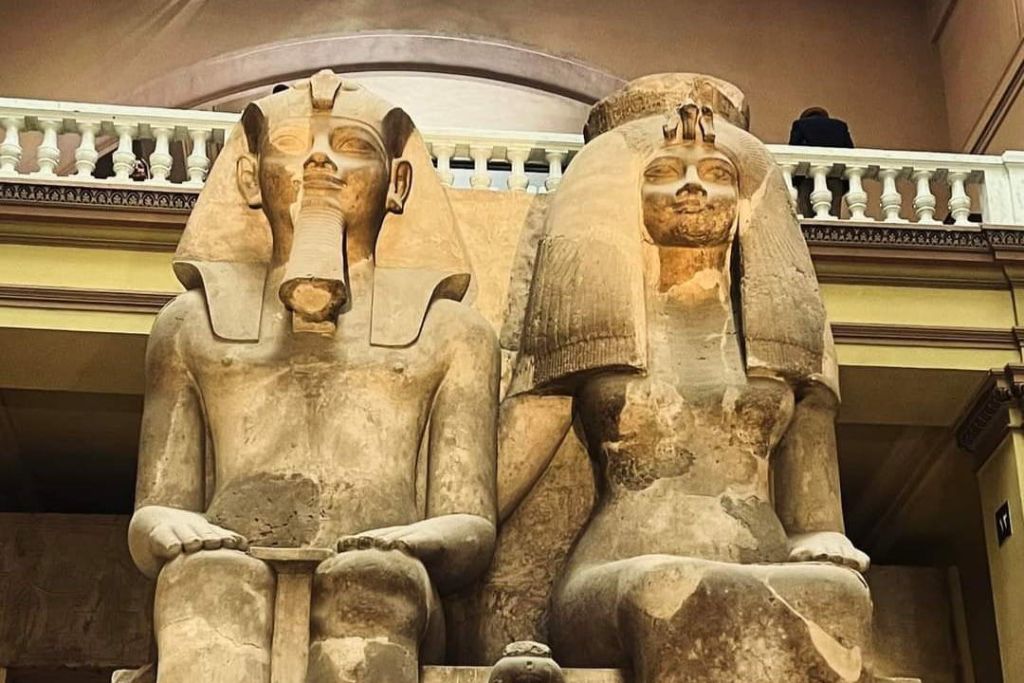 앉아 있는 파라오와 정교한 머리 장식이 있는 모습을 묘사한 두 개의 커다란 고대 이집트 조각상이 실내에 전시되어 있습니다.