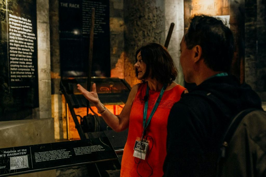 역사적인 전시물과 정보 패널을 배경으로 한 남성을 둘러보는 오렌지색 드레스를 입은 여성.