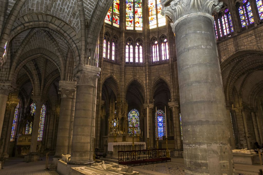 커다란 석조 기둥, 정교한 스테인드글라스 창문, 화려한 제단을 배경으로 한 고딕 양식의 대성당 내부.