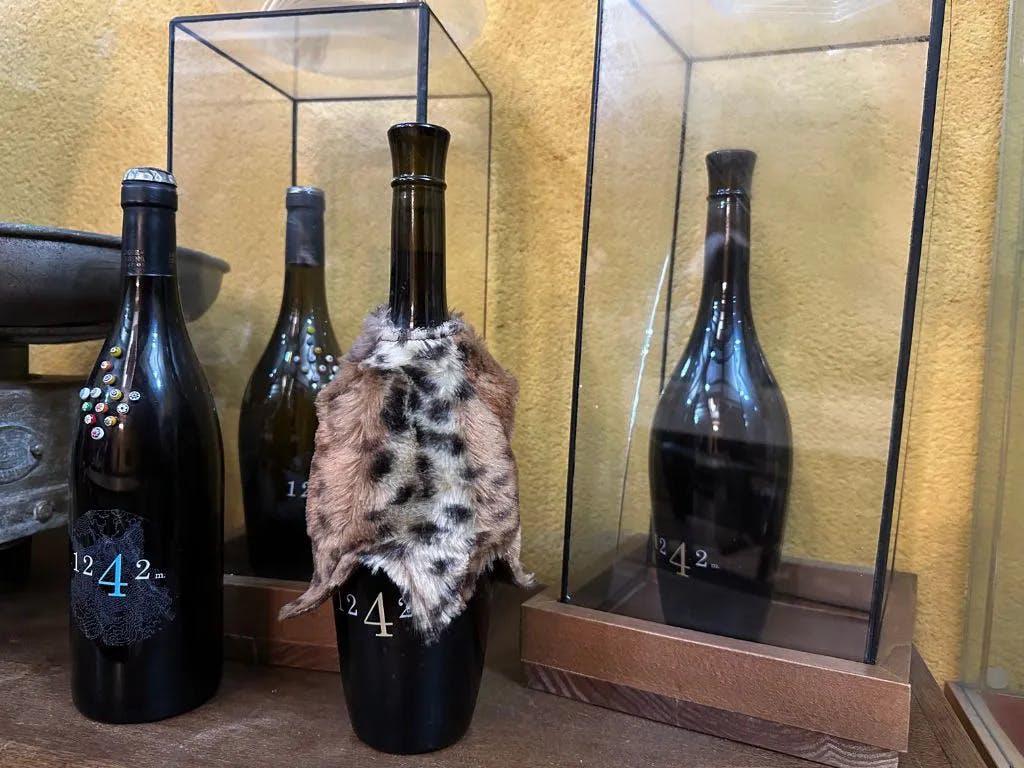 동물 모피로 덮인 와인병이 비슷한 병을 배경으로 유리 케이스에 표시됩니다.