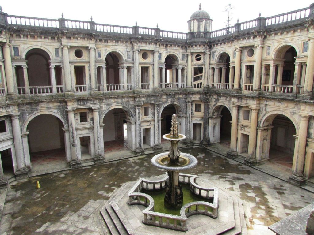 중앙에 화려한 층계 분수가 있는 오래된 석조 안뜰로, 아치형 창문과 출입구가 있는 2층 건물로 둘러싸여 있습니다.