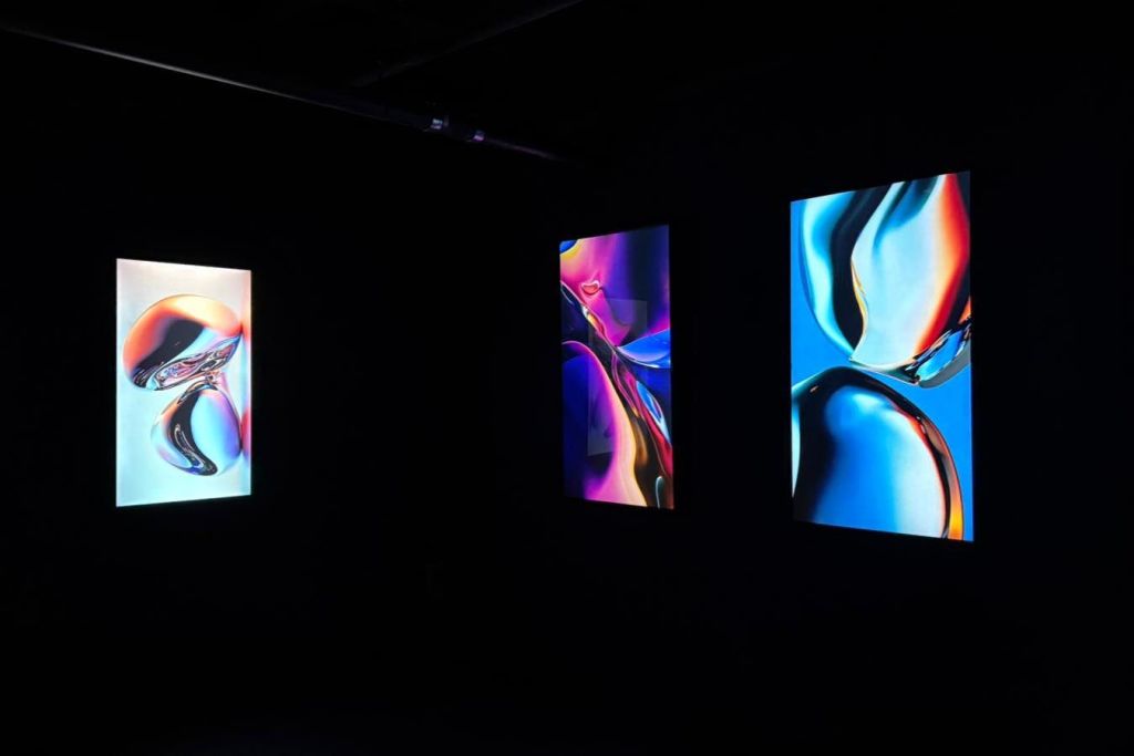 어두운 방에 선명한 색상이 표시된 세 개의 수직 추상 작품.