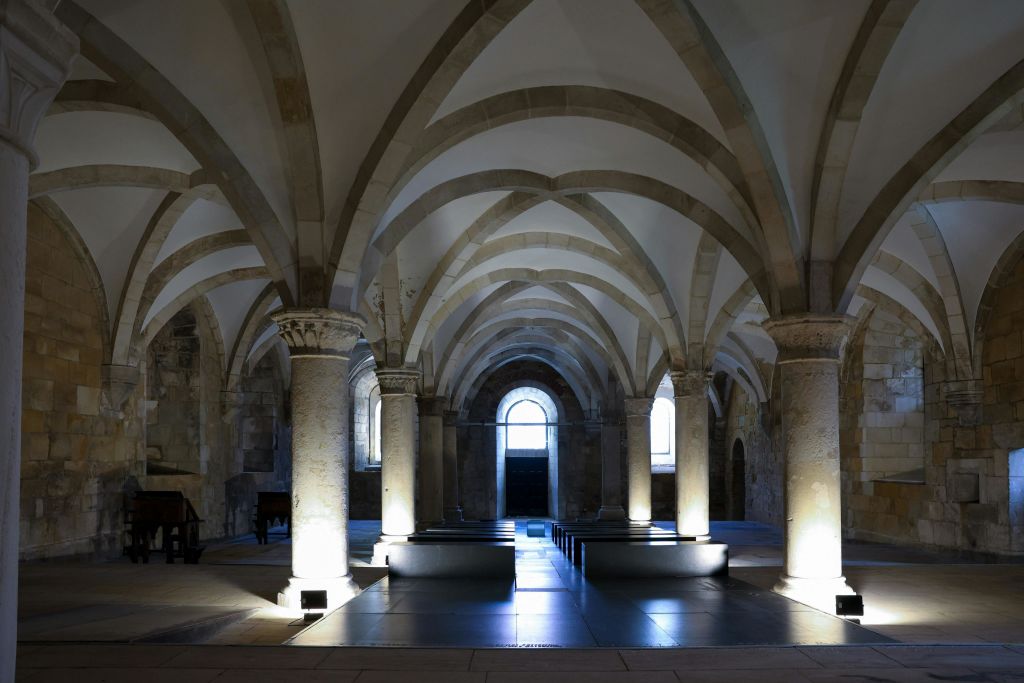 건축학적 디테일을 강조하는 석조 기둥, 아치, 부드러운 조명이 있는 역사적인 아치형 홀의 내부.