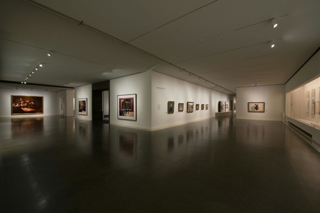흰색 벽에 액자 그림, 광택이 있는 어두운 바닥, 희미한 조명이 있는 미술관. 사람이 없습니다.