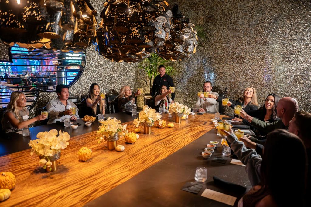 우아하고 꾸며진 방의 나무 테이블 주변에서 축하용 토스트로 안경을 올리는 사람들의 모임.