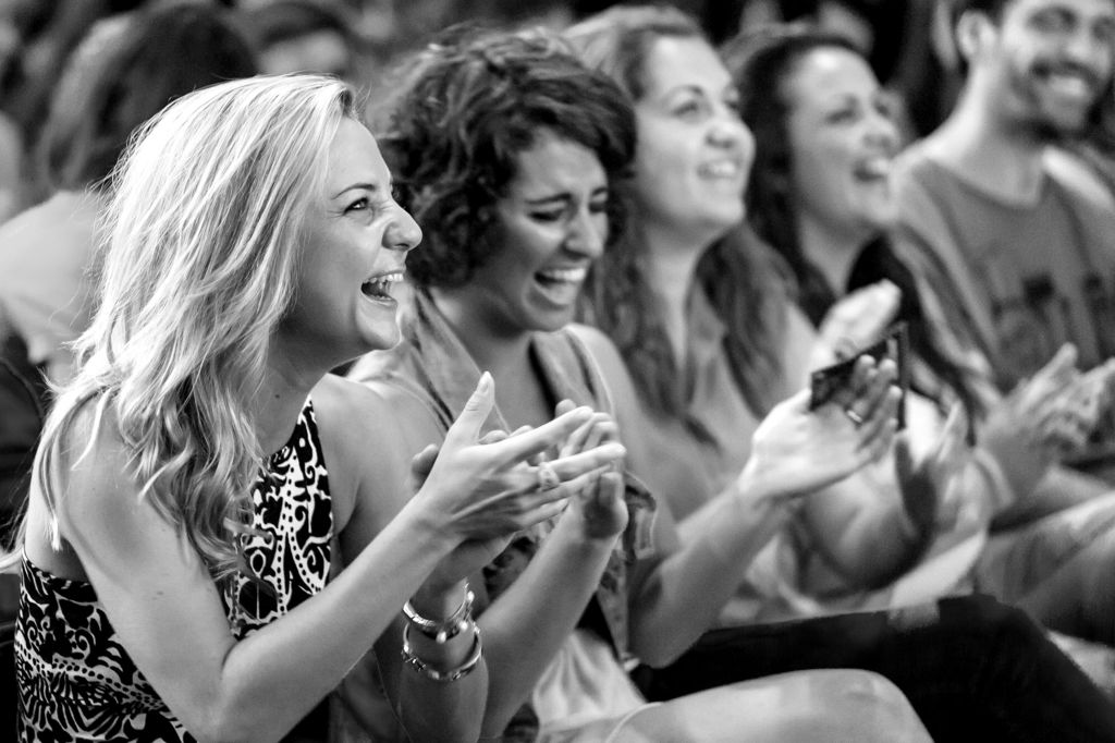 일렬로 앉아 웃으며 박수를 치는 사람들의 모습이 흑백으로 포착되었습니다.