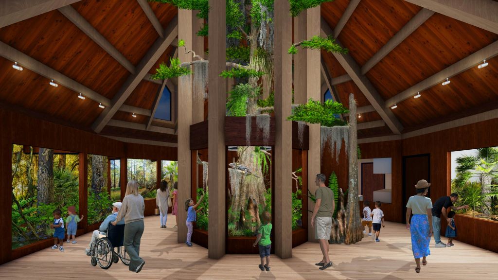 커다란 창문이 있는 목조 건물에 방문객들로 둘러싸인 중앙 나무 디스플레이가 있는 자연 전시물입니다.