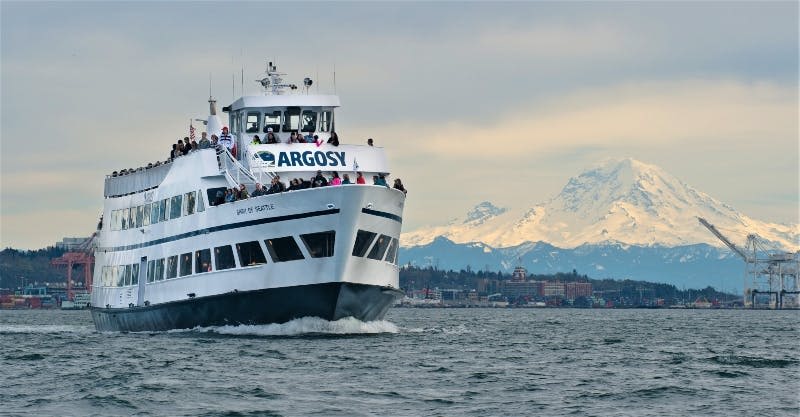 레이니어 산을 배경으로 아르고시 크루즈 보트를 타고 바깥 데크에서 사람들을 만나보세요.