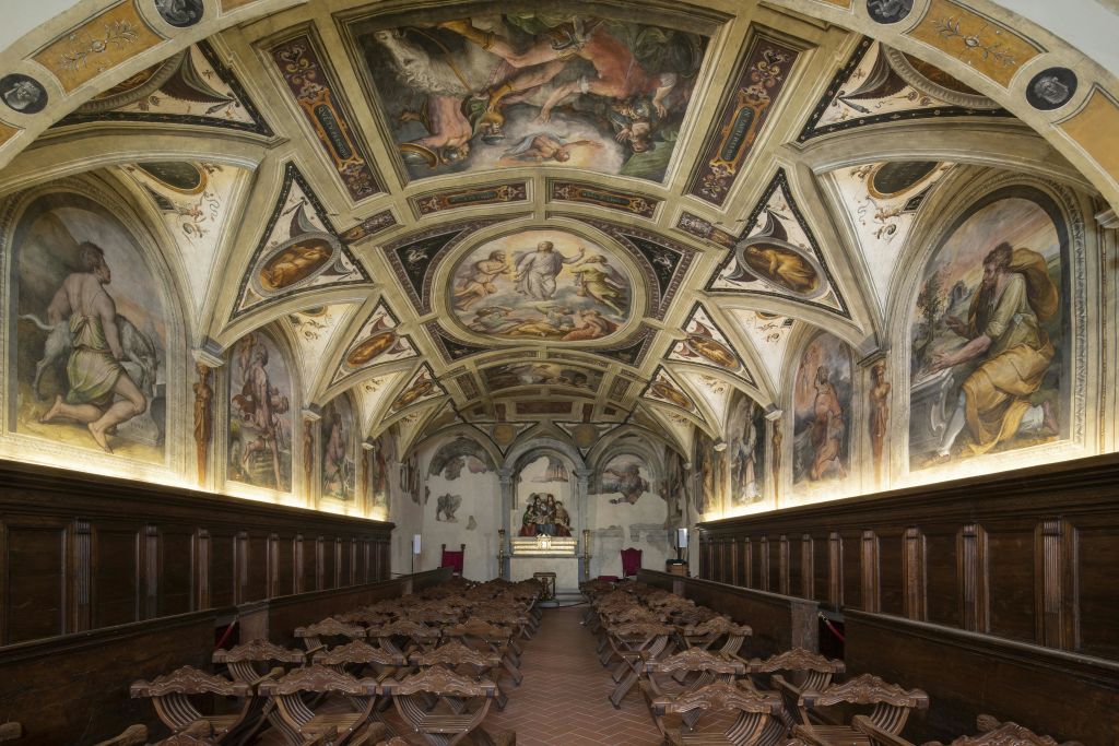 프레스코화로 장식된 화려한 천장형 객실이 벽과 천장을 덮고 있으며, 나무 의자가 가득하고 전면에 작은 제단이 있습니다.