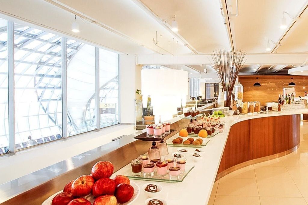 조명이 밝은 방의 곡선형 카운터에 다양한 디저트, 과일, 음료가 진열된 뷔페입니다.