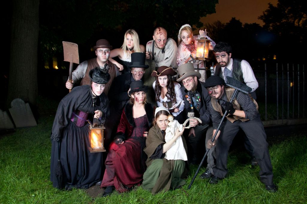 역사적인 의상을 입은 사람들이 등불, 가래, 다양한 소품을 들고 야외에서 포즈를 취하고 있습니다.