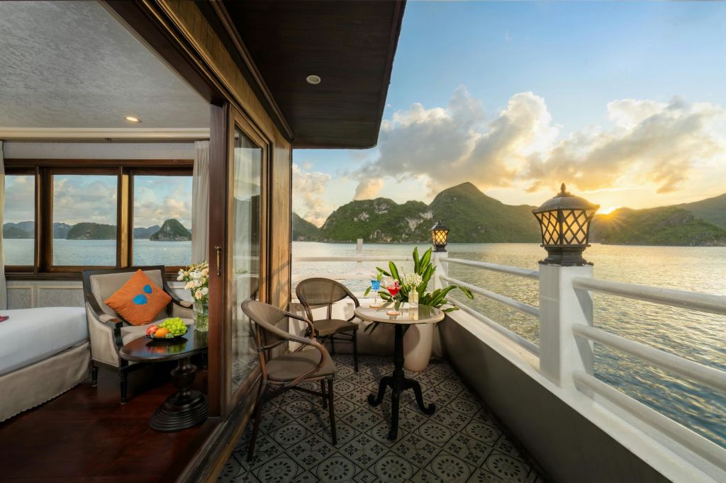산, 물, 석양의 경치를 내려다볼 수 있는 의자와 테이블이 있는 발코니. 난간에는 등불이 장식되어 있습니다.
