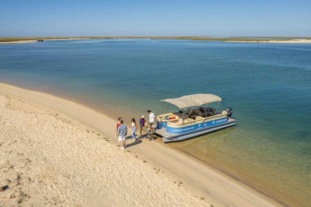 포모사마르 보트에서 내려 맑은 하늘 아래 잔잔한 푸른 바다를 따라 데세르타 섬의 모래 해변으로 향하는 게스트.