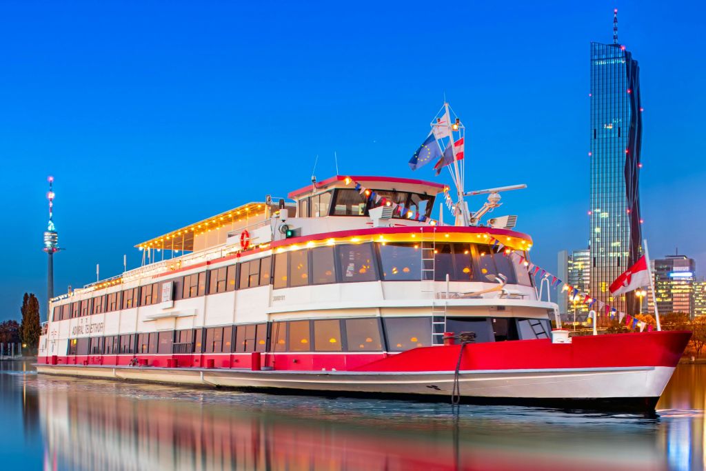 맑고 푸른 저녁 하늘을 배경으로 항구에 정박해 있는 현악기와 깃발로 장식된 흰색과 빨간색 보트.