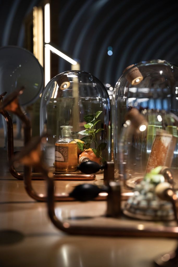 반사 표면에 작은 식물, 병 및 기타 물품을 감싸는 유리 돔이 있는 장식용 디스플레이입니다.