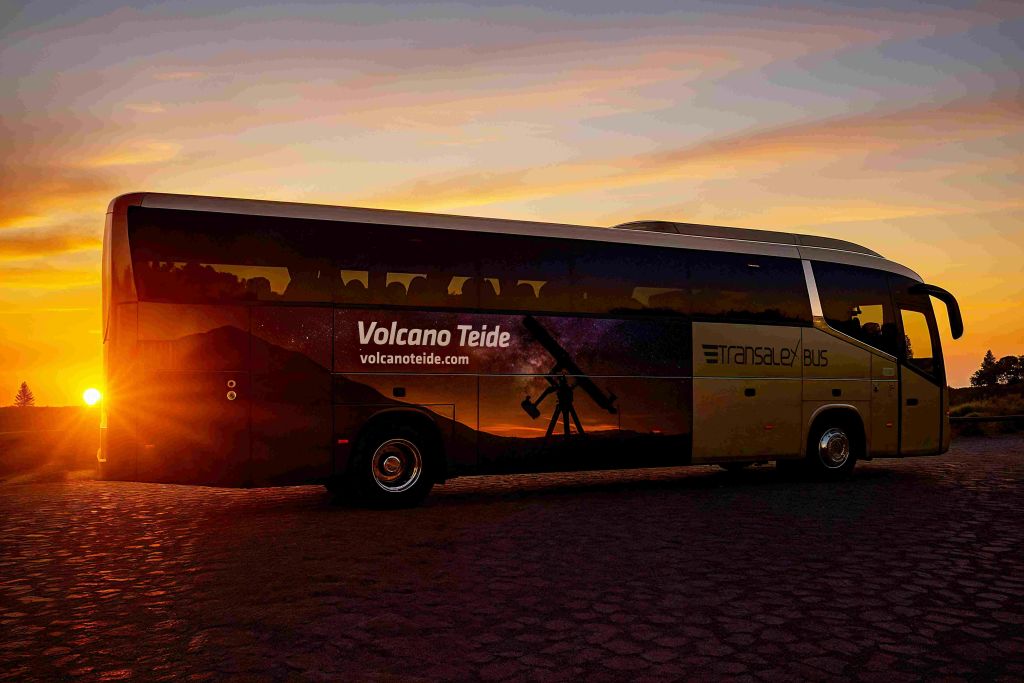 "볼케이노 테이데 (Volcano Teide)" 와 "트랜스알렉스 버스 (transalex bus)" 브랜딩으로 일몰에 주차된 버스로 풍경과 망원경 그래픽을 보여줍니다.