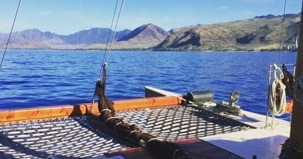 맑은 하늘 아래 산을 배경으로 푸른 바다가 내려다보이는 배의 갑판에서 바라보는 풍경입니다.