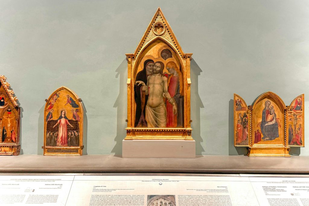 황금빛 화려한 액자의 종교적 장면이 그려진 미술관에 전시된 트리프티치 (triptych) 예술 작품으로, 아래에 묘사된 명판이 있습니다.
