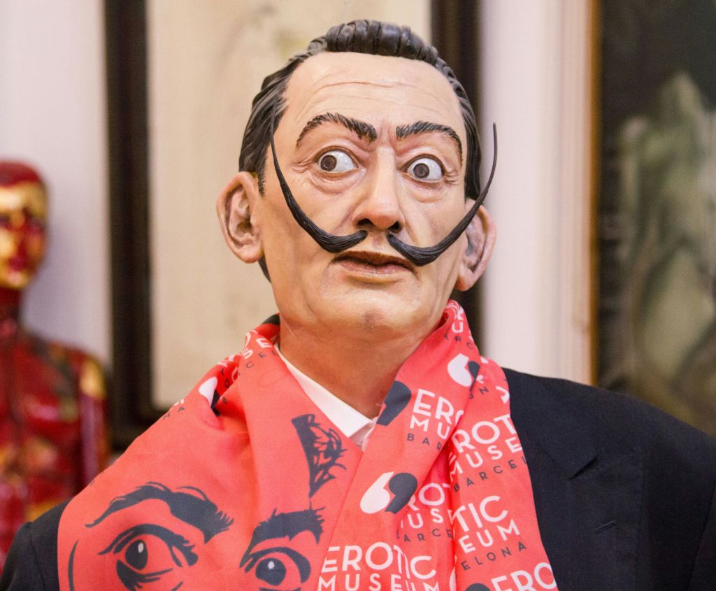 '에로틱 뮤지엄 바르셀로나' 문구가 새겨진 빨간 스카프와 정장을 두른 콧수염이 뚜렷한 남성의 실물과 같은 조각상입니다.